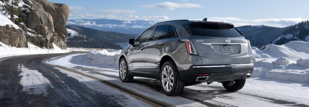 Rear driver angle of a grey 2021 Cadillac XT5 driving in winter