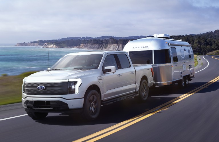 Front driver angle of a silver 2022 Ford F-150 Lightning towing a trailer