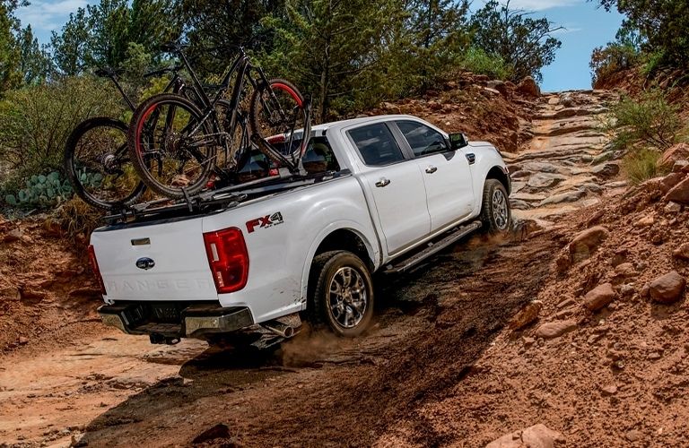 A white 2021 Ford Ranger carrying bicycles uphill