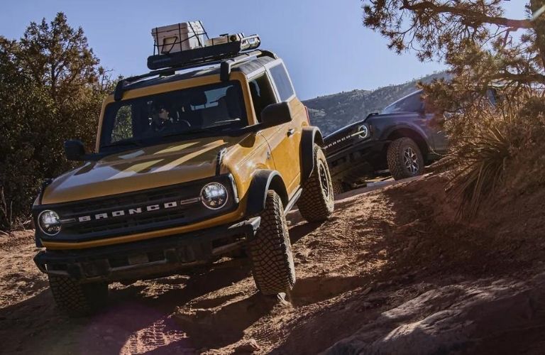 A yellow 2021 Ford Bronco driving on a muddy terrain.