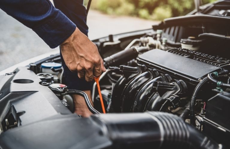 A mechanic using the dipstick method to check engine oil level.