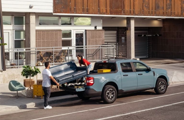 a man and woman loading a couch in the back of a 2022 Ford Maverick™