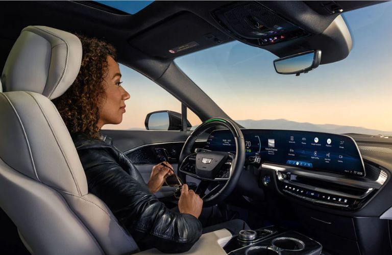 Rear view of a woman seated on the driver's seat inside the 2023 Cadillac Lyriq