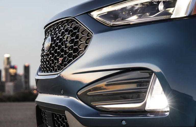 Close-up of bi-LED headlamps and fog lamps with city skyline in the background