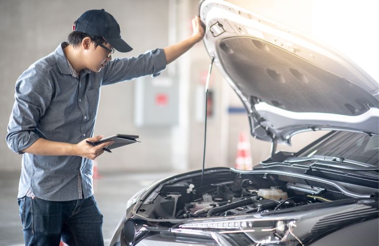 Serviceman inspecting the engine of a vehicle