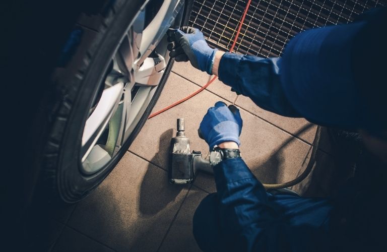 a technician wearing blue gloves repairing the tire of a car
