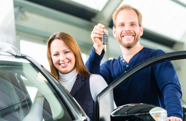 A couple posing with key of their vehicle 