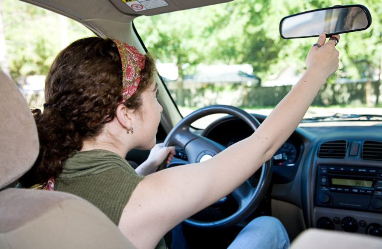 Teenage girl adjusting her vehicle mirror