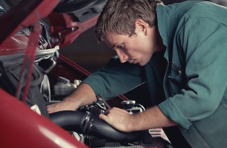 technician working under the hood of a car