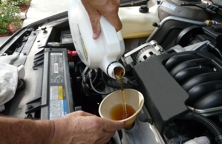 technician pouring fresh oil in a car