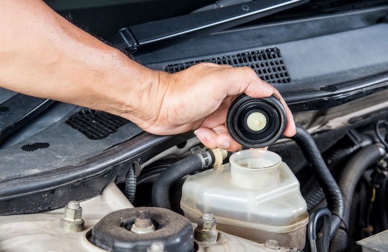 technician pouring brake fluid in a car