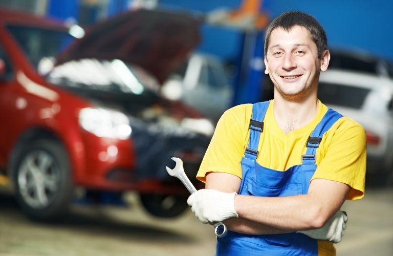 A mechanic posing in front of a vehicle